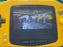 Yellow Game Boy Advance held in a hand with a game displayed on the screen.