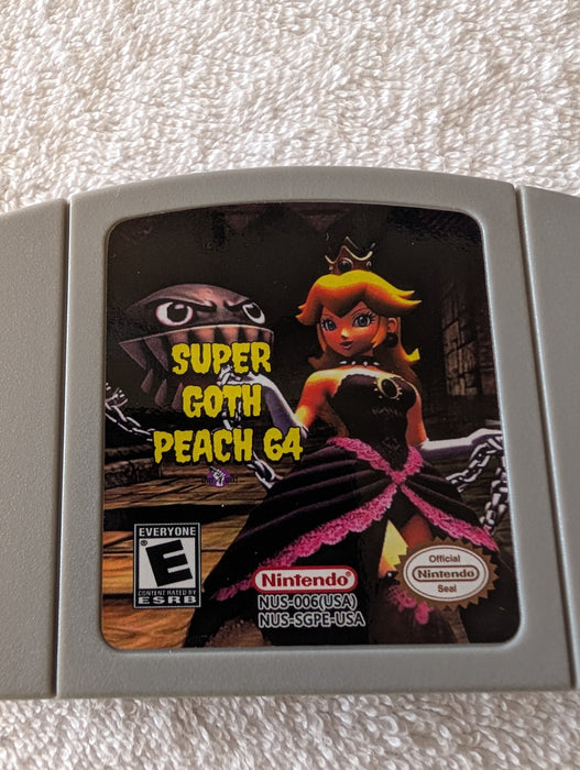 A Nintendo NUS-Game 4 retro game cartridge for 'Super Goth Peach 64' resting on a white textured fabric background. The cartridge features artwork of Peach in a black dress with pink accents and a gold crown, alongside a dark gothic character.